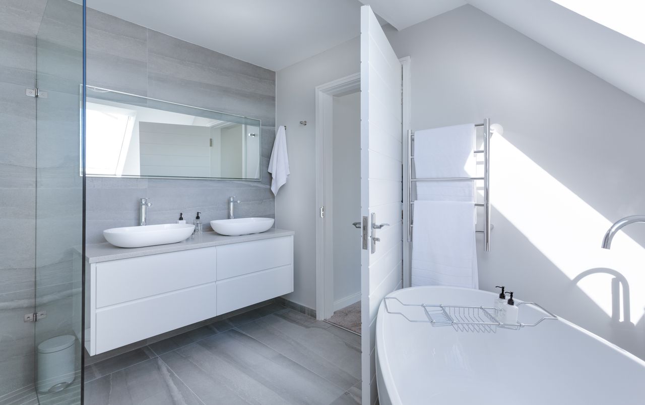 gallery-3 Sleek contemporary bathroom with bathtub and twin sinks, showcasing minimalist design and luxury.